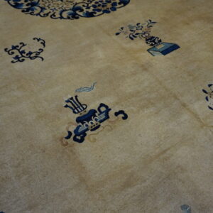A low-pile tan rug features scattered dark blue floral and symbolic object patterns.