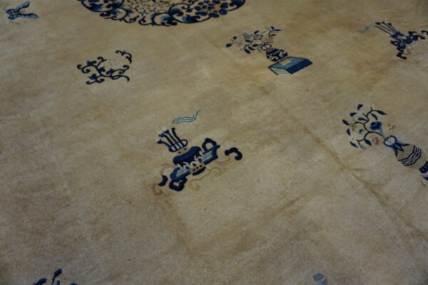 A low-pile tan rug features scattered dark blue floral and symbolic object patterns.