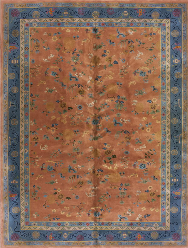 Orange-rust rug with scattered blue and yellow florals, framed by wide borders of ornate slate blue.