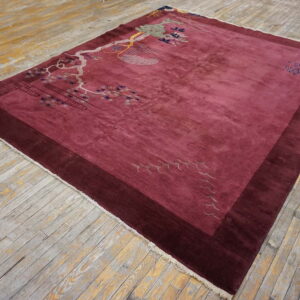 Rectangular magenta rug with scenic branch patterns and a dark border rests on worn wood planks.