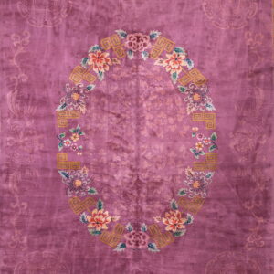 A high-pile magenta rug featuring a central oval medallion with colorful peach, green, and yellow floral designs.