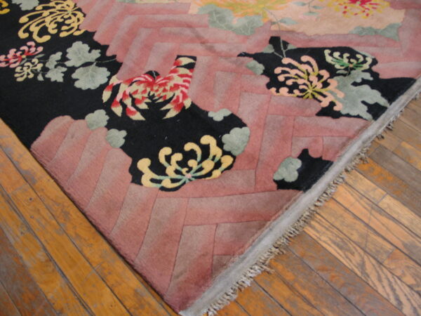 High-pile rug features black stylized flowers, pink zigzag details, and visible fringe on wood planks.