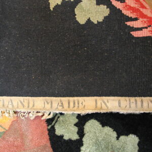 Black ribbed rug backing with "HAND MADE IN CHINA" label exposes the colorful floral front underneath.