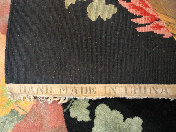 Black ribbed rug backing with "hand made in china" label exposes the colorful floral front underneath.