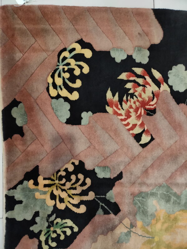 High-pile rug featuring carved yellow and red flowers on black, surrounded by a pink diagonal border.