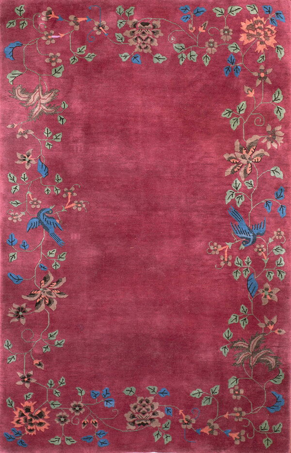 Deep red rug featuring a vine and floral border with blue birds on the scrolling sides.