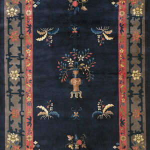 Navy blue rug with scattered yellow and pink botanical motifs framed by a taupe and coral patterned border.