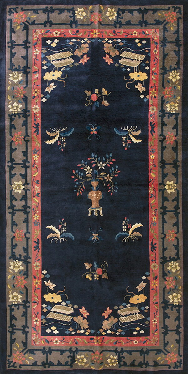 Navy blue rug with scattered yellow and pink botanical motifs framed by a taupe and coral patterned border.