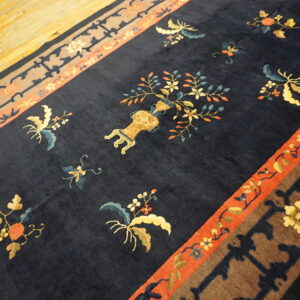 Plush navy rug with ornate botanical patterns and a central vase motif resting on light wood floors.