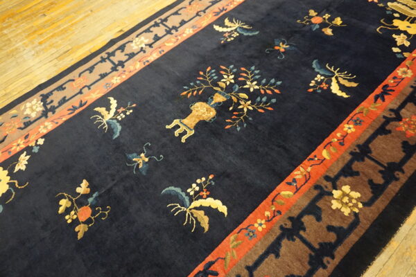 Plush navy rug with ornate botanical patterns and a central vase motif resting on light wood floors.
