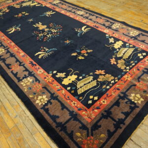 A large, plush navy rug with colorful floral motifs and multiple borders on aged wood floors.