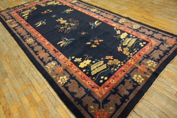 A large, plush navy rug with colorful floral motifs and multiple borders on aged wood floors.