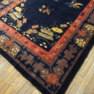 Plush navy rug with floral motifs and borders in brown and terracotta, resting on light wood planks.