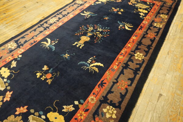Dark blue area rug with yellow, orange, and teal floral patterns and layered brown and red borders.