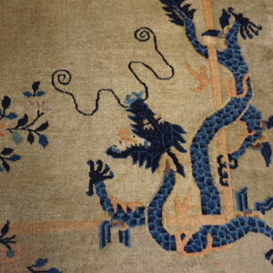 Muted green rug with an ornate blue dragon and peach motifs displayed on light plank flooring.