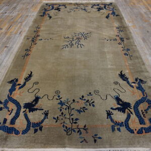 Green high-pile rug featuring blue dragon motifs and floral borders on weathered wood flooring.