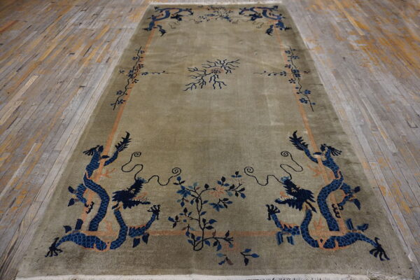 Green high-pile rug featuring blue dragon motifs and floral borders on weathered wood flooring.