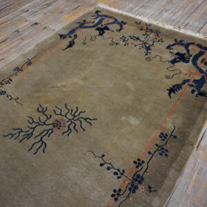 Muted green low-pile rug featuring intricate blue dragon and floral motifs on rustic plank flooring.