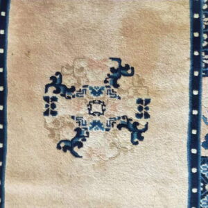 Beige rug with dark blue central design and patterned side borders featuring light blue florals.