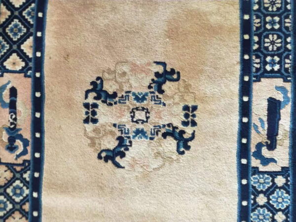 Beige rug with dark blue central design and patterned side borders featuring light blue florals.