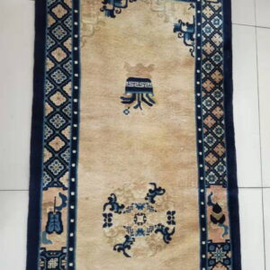 Light tan runner rug with a wide navy blue border and abstract blue and beige patterned motifs on tile.