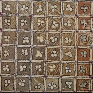 Muted brown and russet hooked rug with a checkerboard pattern and light floral motifs in each square.