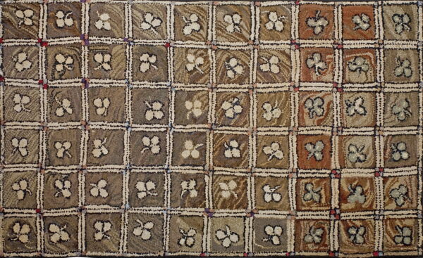 Muted brown and russet hooked rug with a checkerboard pattern and light floral motifs in each square.