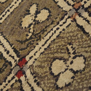 Textured high-pile rug detail showing a beige and dark brown geometric pattern with subtle red and purple accents.