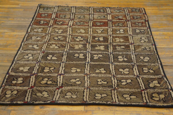 Textured rug with a brown, tan, and red checked pattern featuring beige floral motifs on a wood floor.