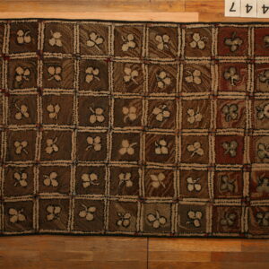 Brown and tan checkerboard rug featuring textured floral squares resting on wood plank flooring.