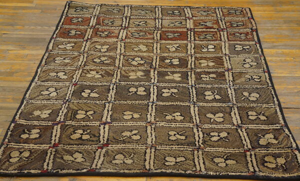 Textured brown and tan rug featuring a square grid pattern with stylized floral motifs on wood planks.