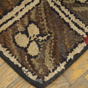 Highly textured brown, black, and beige patterned rug corner rests on worn diagonal wood flooring.