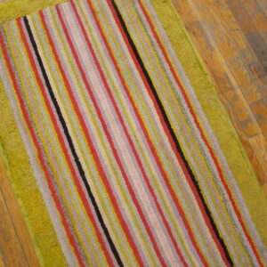 A colorful striped runner rug featuring a wide, textured lime green border rests on wood flooring.