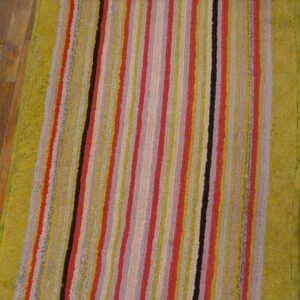 Textured runner rug with multicolor vertical stripes and wide green borders on wood flooring.