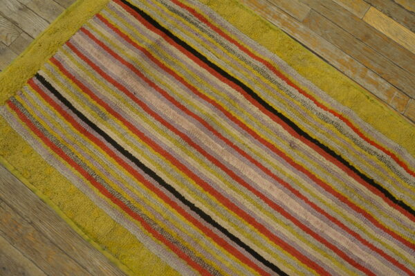 Multi-colored striped rug with a thick chartreuse border on weathered wooden plank flooring.