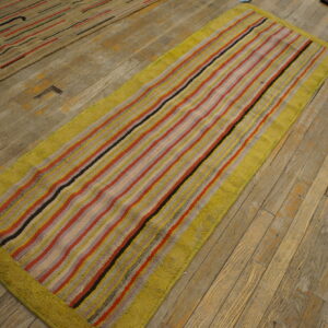 High-pile runner rug with colorful vertical stripes and a chartreuse border on distressed plank wood floors.