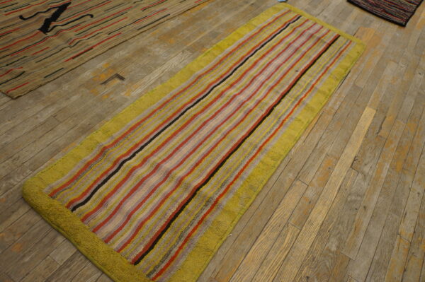 High-pile runner rug with colorful vertical stripes and a chartreuse border on distressed plank wood floors.