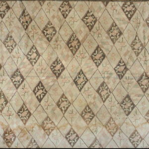 Muted beige rug with a diamond trellis pattern containing pink and green floral designs.