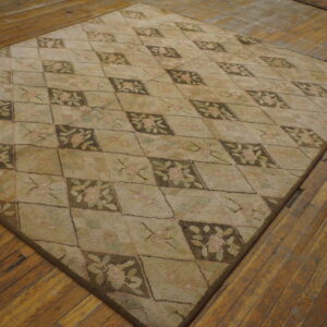 A nubby textured beige and brown rug with floral diamonds lays on rustic hardwood planks.
