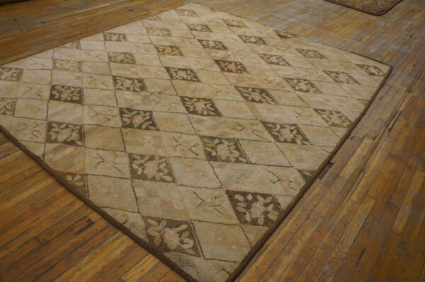 A nubby textured beige and brown rug with floral diamonds lays on rustic hardwood planks.