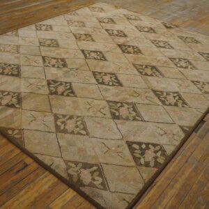 Beige rug with pale pink and dark brown floral diamond patterns covers rustic wood flooring.