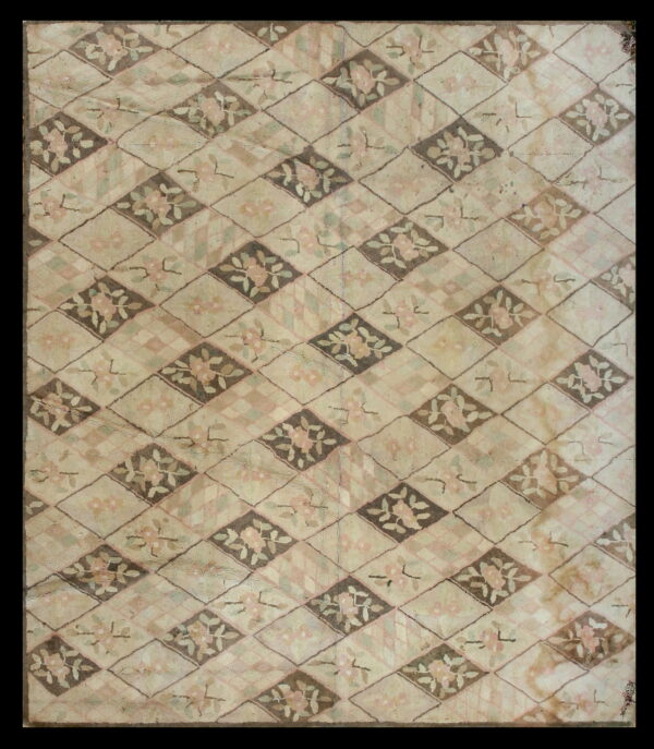 A textured beige rug features a repeating diamond pattern with pink floral motifs on taupe and light backgrounds.