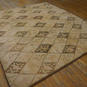 Low pile beige hooked rug with brown and pink floral diamond pattern on wood flooring.