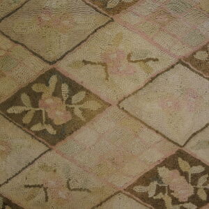 Muted tan rug with nubby texture displays a diamond trellis pattern containing pink and brown florals.