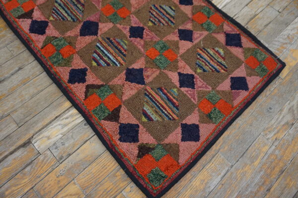 High-pile brown rug with pink, navy, orange, and striped geometric patch squares on distressed wood flooring.