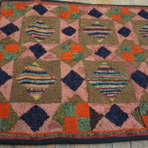 Patchwork geometric rug with pink, brown, navy, and orange textures on light wooden floorboards.