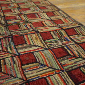 Highly textured runner with geometric red squares and multicolored rag strips on wood flooring.