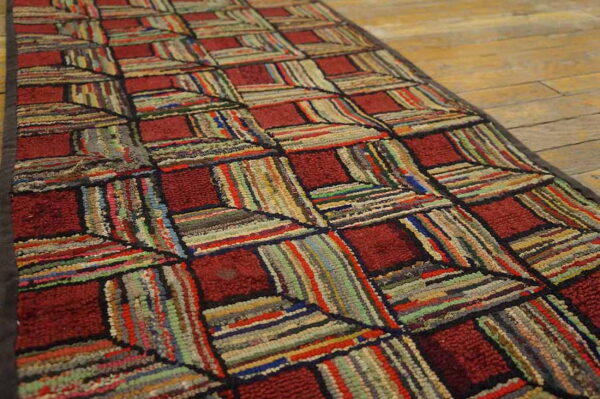 Highly textured runner with geometric red squares and multicolored rag strips on wood flooring.