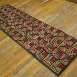 A textured runner features a red and multicolored striped lattice pattern on worn wood floors.