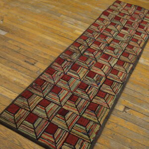 Textured runner rug with multicolored striped blocks and dark red squares on light hardwood flooring.